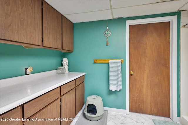 bathroom featuring marble finish floor, a paneled ceiling, and baseboards