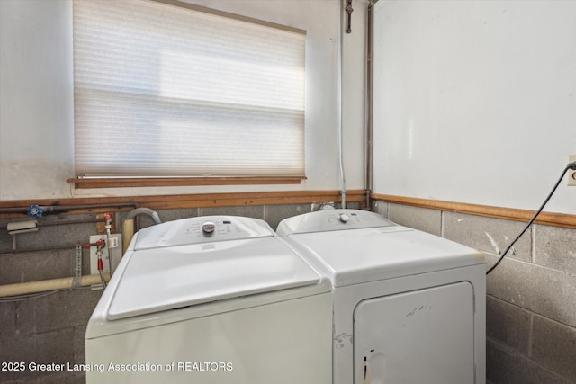 laundry area with a wainscoted wall, washer and dryer, and laundry area