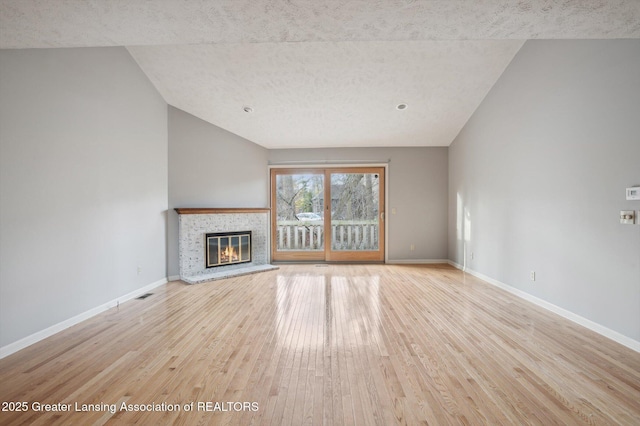 unfurnished living room with a glass covered fireplace, visible vents, baseboards, and wood finished floors