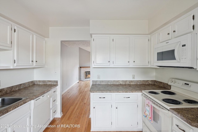 kitchen featuring a glass covered fireplace, white appliances, white cabinets, and light wood finished floors