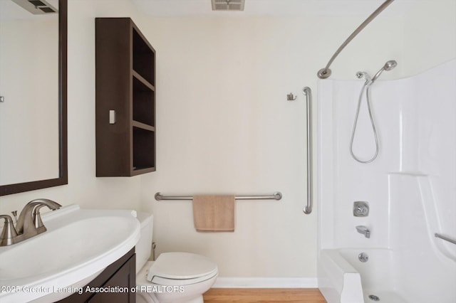 bathroom with baseboards, toilet, shower / bathing tub combination, wood finished floors, and vanity