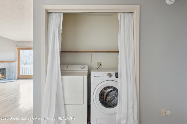 laundry room featuring a glass covered fireplace, laundry area, and washing machine and clothes dryer