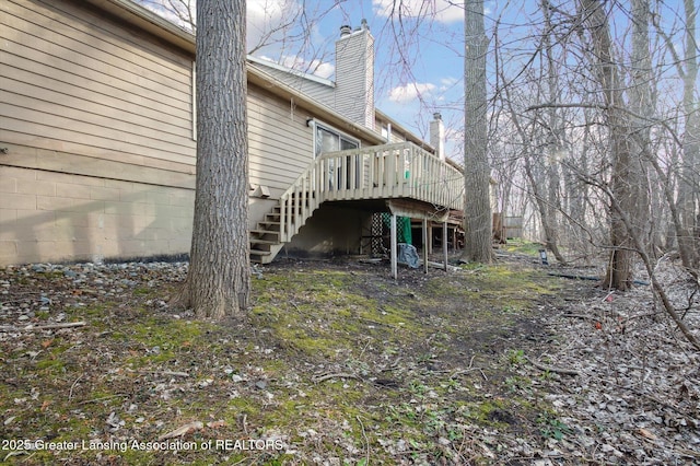 exterior space featuring a wooden deck, a chimney, and stairs