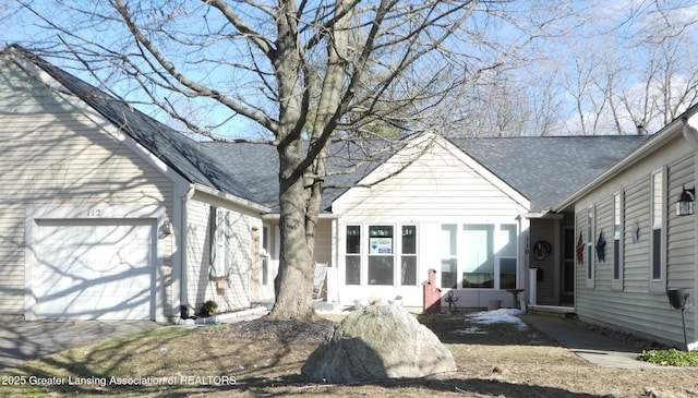 exterior space with a shingled roof and a garage