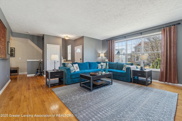 living area with baseboards, wood-type flooring, and a textured ceiling