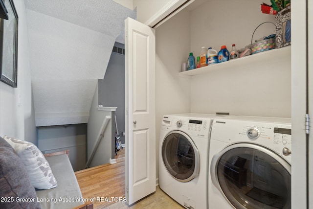 laundry area with laundry area, light wood-type flooring, and washer and clothes dryer