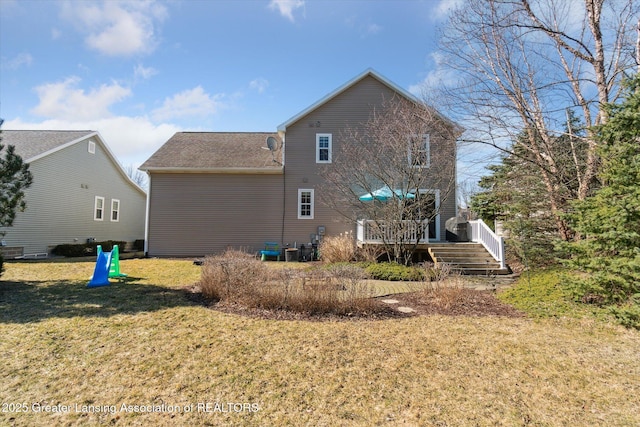 rear view of property featuring central air condition unit, a lawn, and a deck