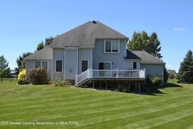 rear view of house with a yard, a wooden deck, and a shingled roof