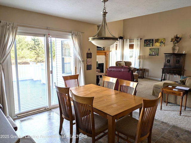 carpeted dining space featuring visible vents, baseboards, and a tile fireplace