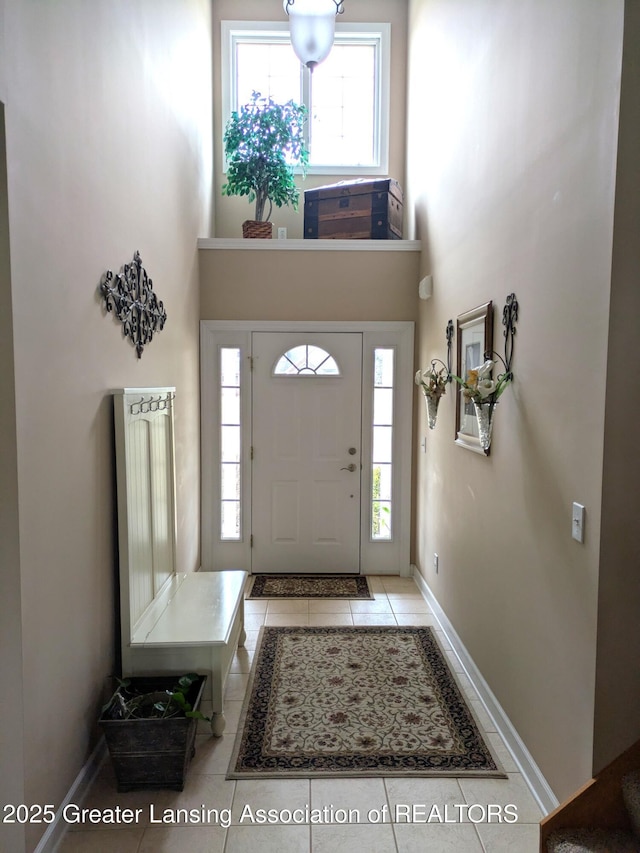 tiled foyer entrance featuring a high ceiling and baseboards