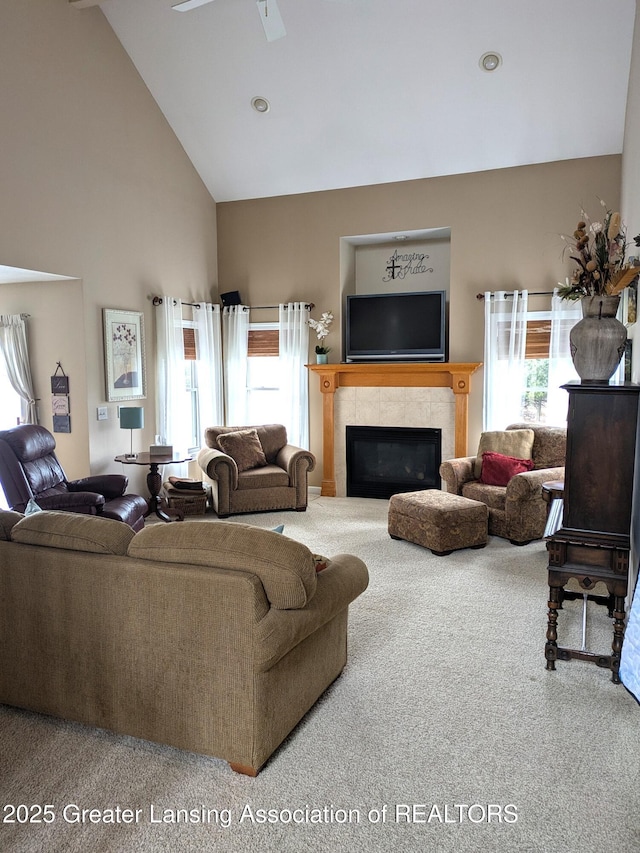 carpeted living area with high vaulted ceiling, plenty of natural light, a ceiling fan, and a premium fireplace