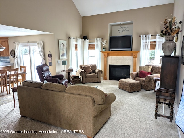 carpeted living room with a glass covered fireplace and high vaulted ceiling