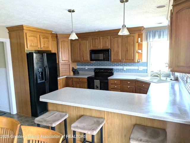 kitchen featuring black appliances, a sink, a peninsula, light countertops, and decorative backsplash