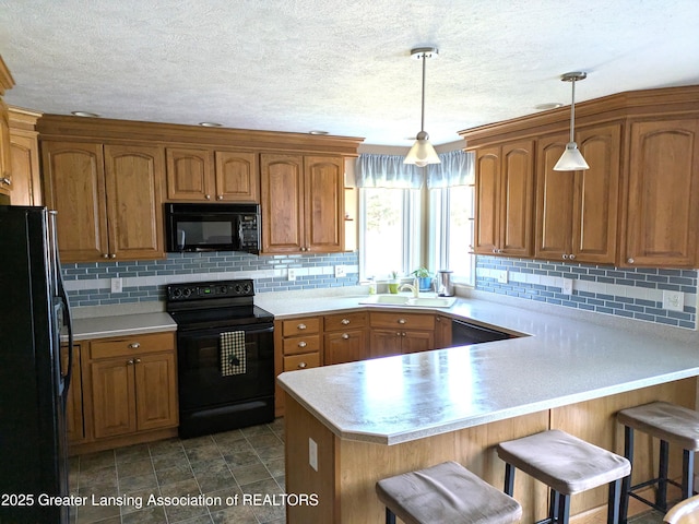 kitchen with black appliances, a peninsula, brown cabinets, and a sink