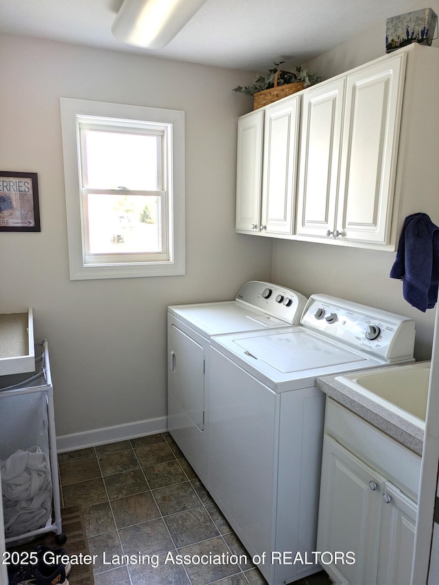 clothes washing area with baseboards, cabinet space, and washing machine and clothes dryer