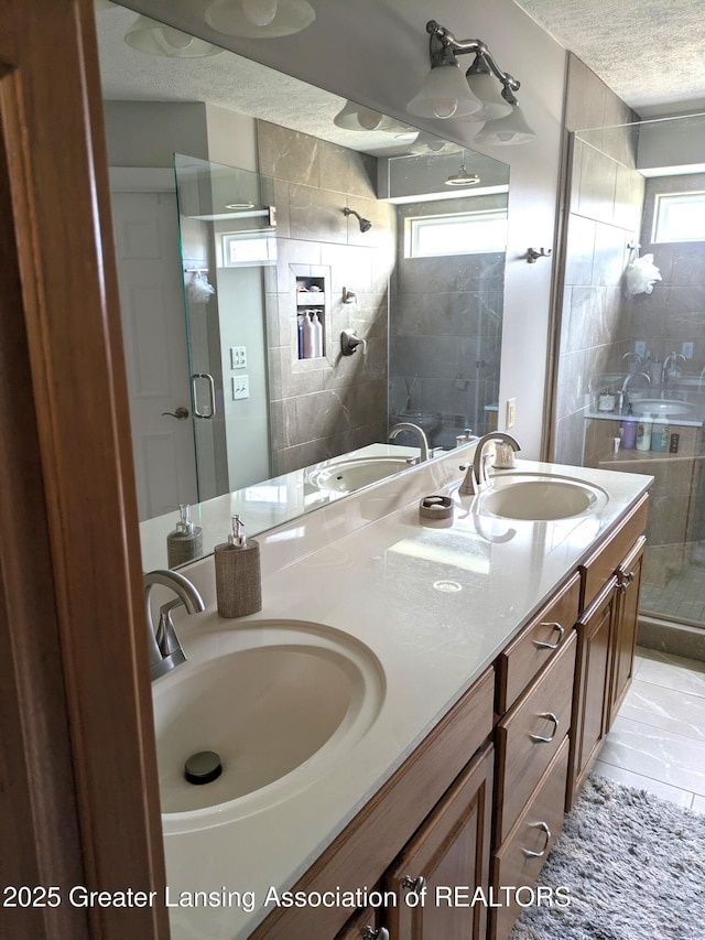 full bathroom with a shower stall, a textured ceiling, and a sink