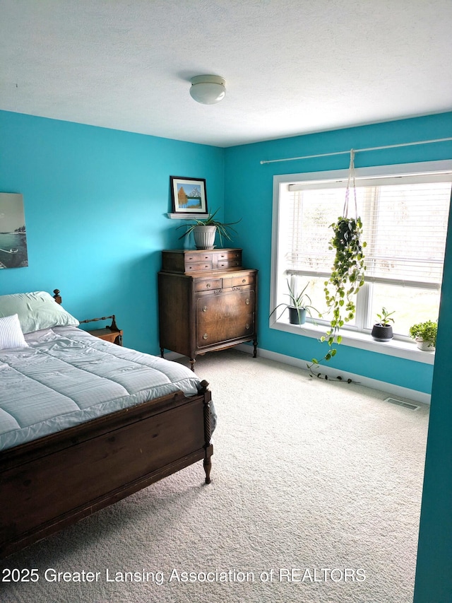 carpeted bedroom with visible vents, baseboards, and a textured ceiling