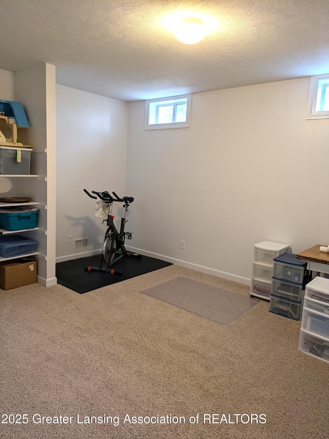 workout room featuring baseboards, visible vents, a textured ceiling, and carpet