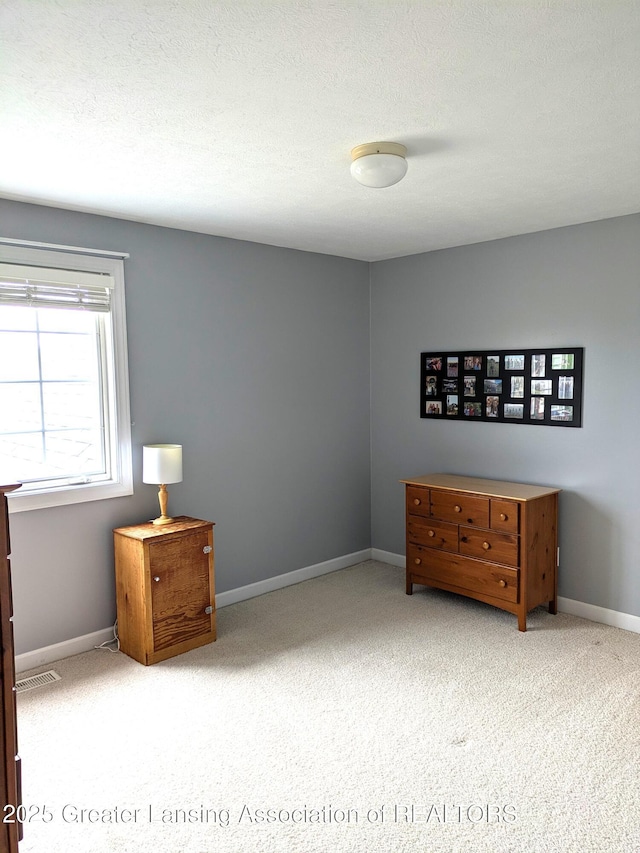 unfurnished bedroom featuring visible vents, baseboards, a textured ceiling, and carpet