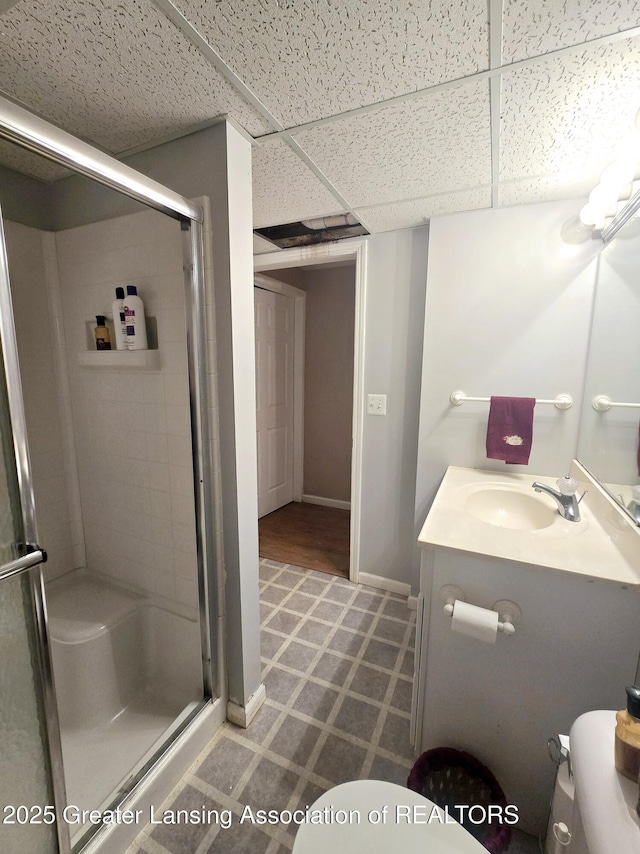 bathroom with a shower stall, toilet, vanity, and baseboards