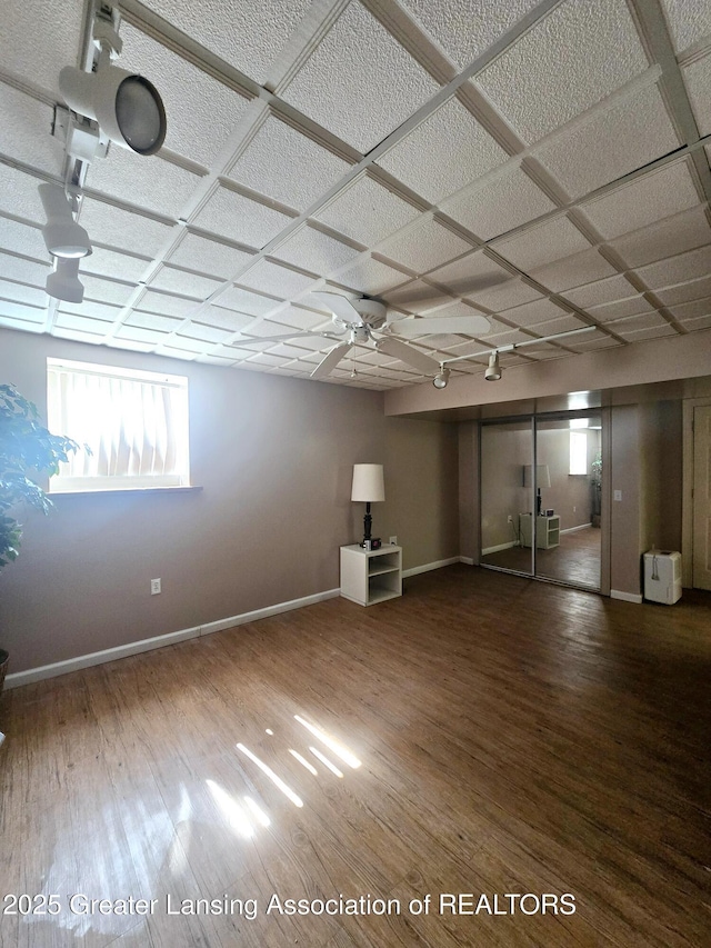 below grade area featuring a ceiling fan, baseboards, and wood finished floors