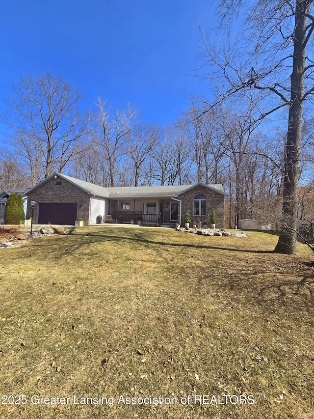 view of front of property with brick siding, covered porch, a front lawn, and a garage