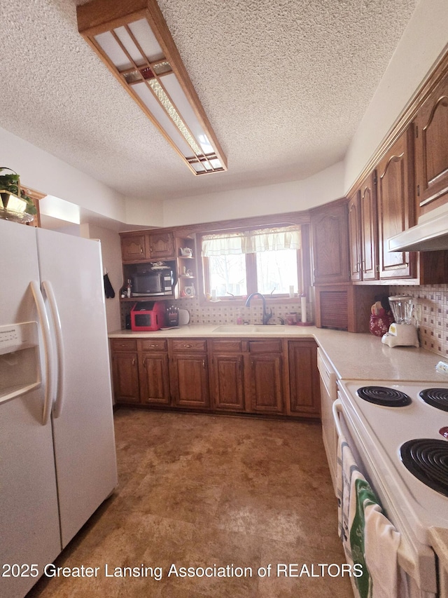 kitchen featuring white appliances, a sink, decorative backsplash, light countertops, and brown cabinets