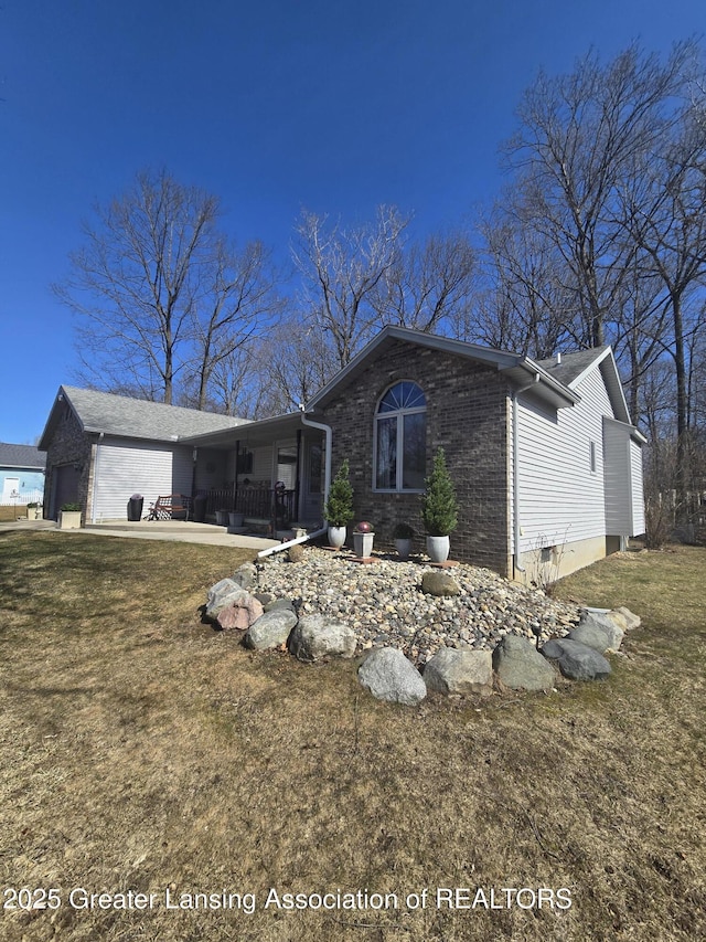 view of front facade with a front yard, brick siding, and a garage