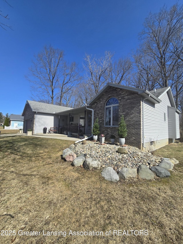 view of front of home with a garage, brick siding, and a front yard