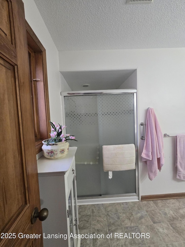 full bathroom with mail area, a stall shower, a textured ceiling, and visible vents