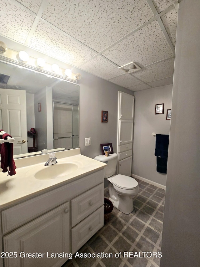 bathroom with a drop ceiling, toilet, vanity, and visible vents