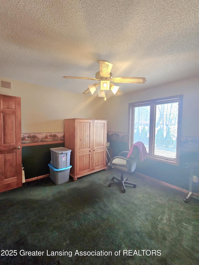 unfurnished bedroom with visible vents, a textured ceiling, carpet flooring, and a ceiling fan