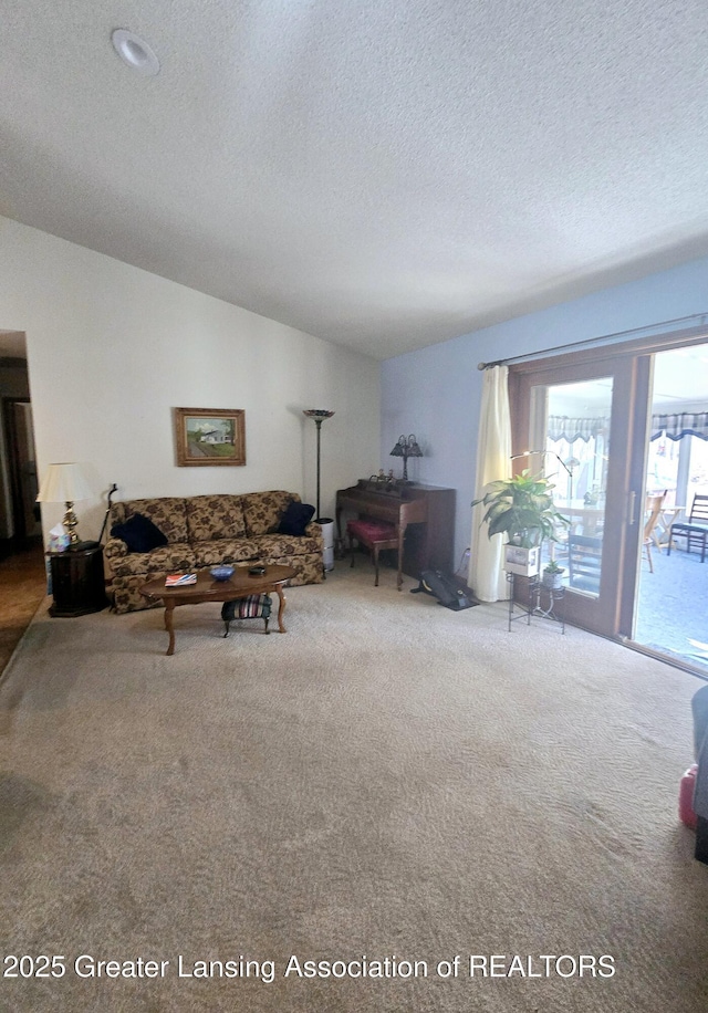 carpeted living area with a textured ceiling and vaulted ceiling