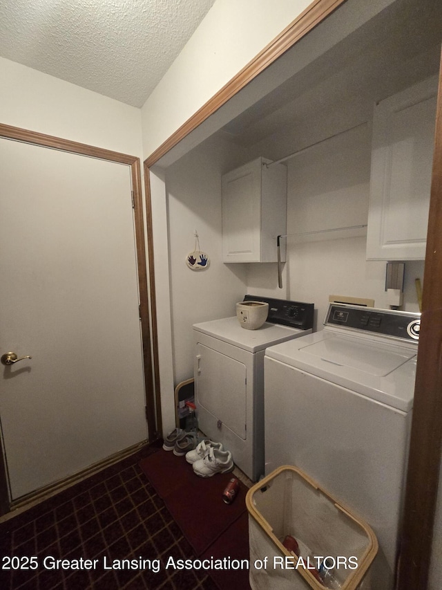 laundry room featuring cabinet space, a textured ceiling, and washing machine and clothes dryer