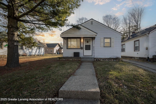 bungalow-style home featuring a yard and cooling unit