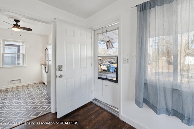 foyer entrance featuring dark wood-type flooring, a ceiling fan, and baseboards