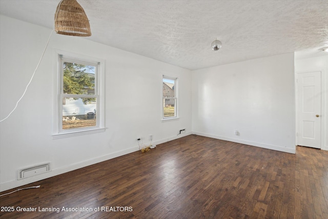 unfurnished room with a textured ceiling, a healthy amount of sunlight, and dark wood-style floors