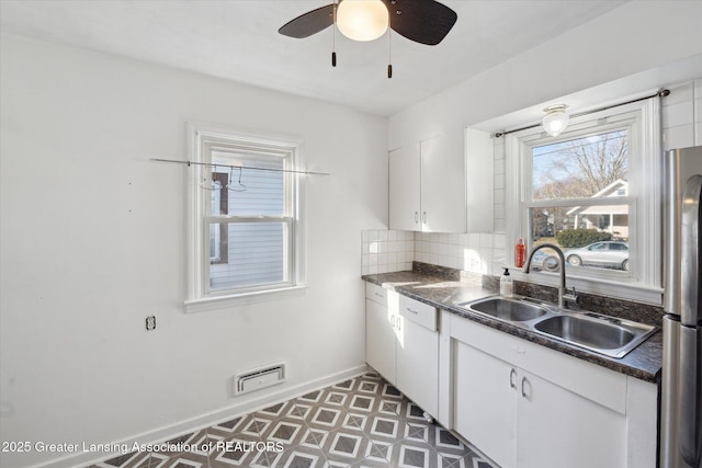 kitchen with freestanding refrigerator, a sink, white cabinets, dark countertops, and tasteful backsplash