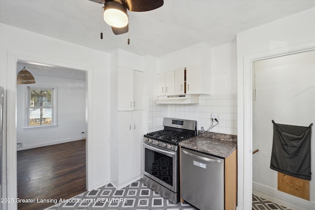 kitchen with under cabinet range hood, dark countertops, white cabinetry, stainless steel appliances, and ceiling fan