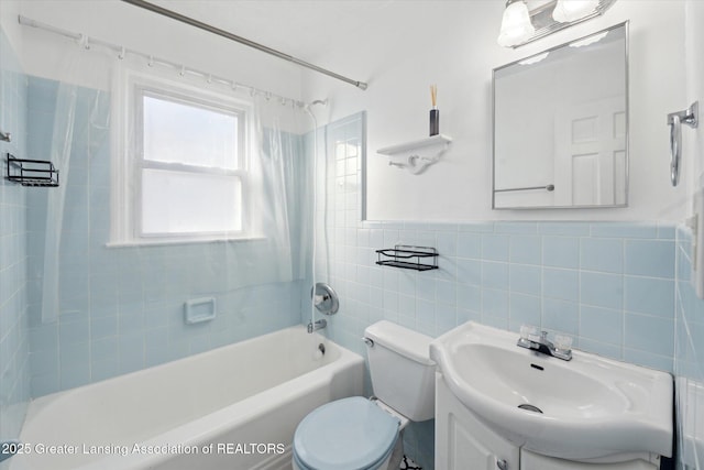 bathroom with toilet, tile walls, wainscoting, washtub / shower combination, and vanity