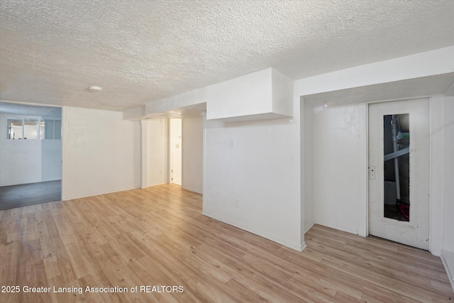 empty room with a textured ceiling and light wood finished floors