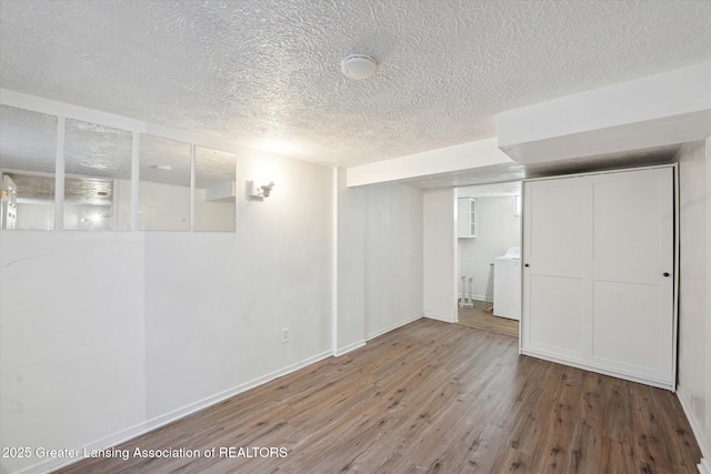 finished basement with washer / dryer, a textured ceiling, baseboards, and wood finished floors