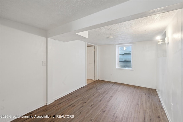 unfurnished room with baseboards, a textured ceiling, and wood finished floors