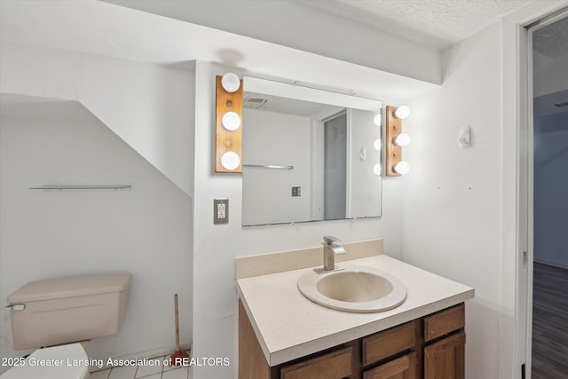 half bath featuring toilet, a textured ceiling, and vanity