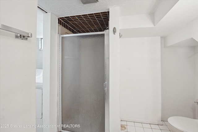 bathroom featuring a textured ceiling, a stall shower, tile patterned flooring, and toilet