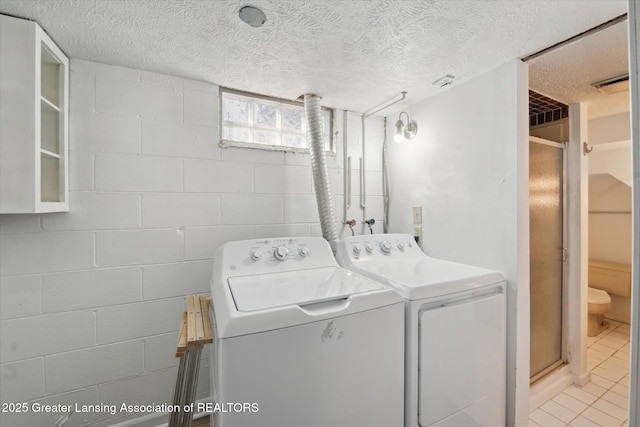 laundry area featuring light tile patterned floors, visible vents, laundry area, a textured ceiling, and washing machine and dryer