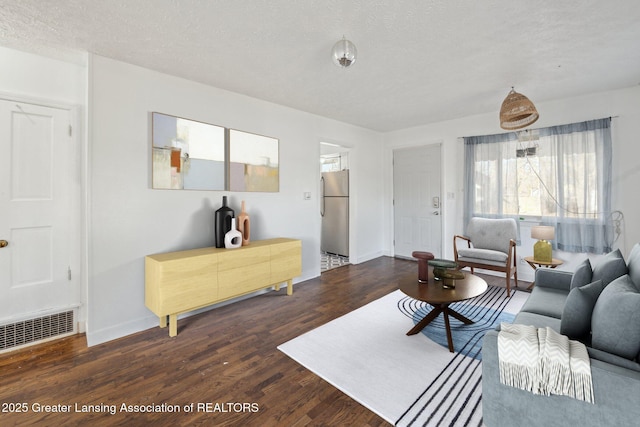 living area featuring visible vents, a textured ceiling, baseboards, and wood finished floors