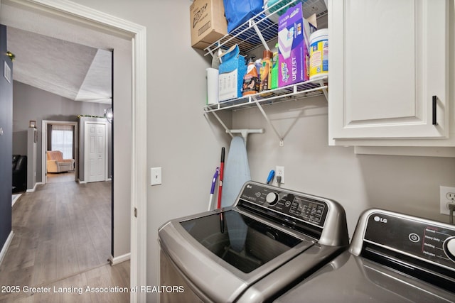 laundry area featuring wood finished floors, cabinet space, baseboards, and washer and clothes dryer