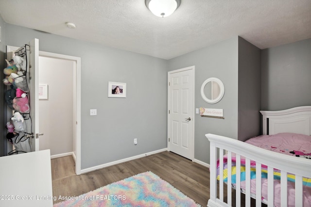 bedroom with baseboards, a textured ceiling, and wood finished floors