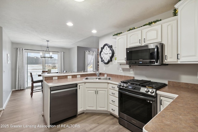 kitchen featuring a sink, stainless steel appliances, a peninsula, and white cabinets